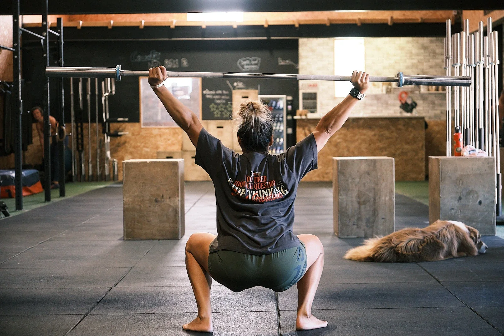 Une adhérente travaille un squat avec une barre dans la box No Plan B